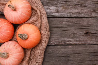 Turuncu balkabakları, kaba ahşap masa zemininde çuval bezi. Üst görünüm, boşluğu kopyala. Yemek, tatil, Şükran Günü, hasat mevsimi konsepti. 