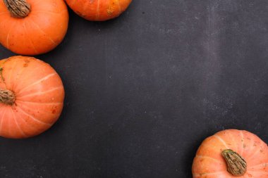 Koyu gri arka planda turuncu balkabağı sınırı. Üst görünüm, boşluğu kopyala. Yemek, tatil, Şükran Günü, hasat mevsimi konsepti