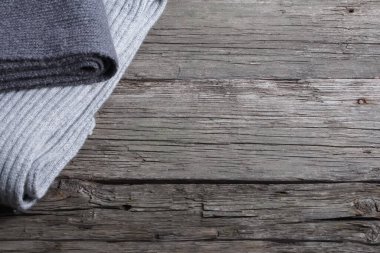 Eski ahşap tahtaların üzerinde katlanmış gri eşarplar. Uzayı kopyala, üst görünüm. Sonbahar arka plan, sonbahar mevsimi, kış, sıcak giysi konsepti