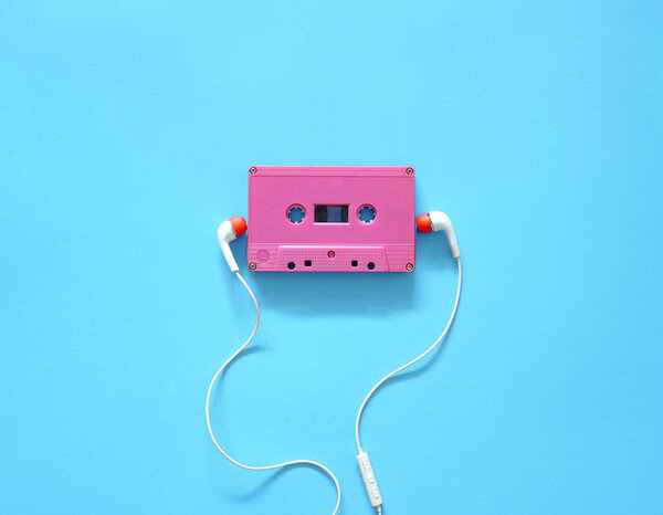 Audio cassette and earphones on a blue background. Musical concept. Minimal style.