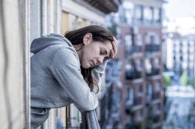 Latin woman standing on balcony feeling overwhelmed and suffering depression