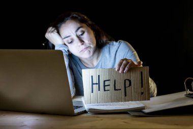 Genç yorgun ve stresli öğrenci yardım işareti tutarak laptop gece geç saatlerde çalışma.