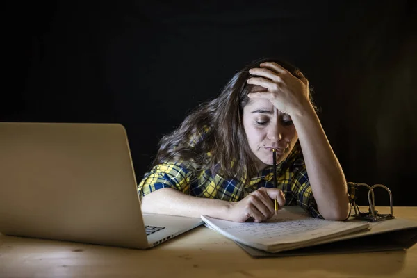 過労の女子大学生の頭を押しながら眠りに落ちるようにしてラップトップに取り組んで格子縞のシャツ — ストック写真
