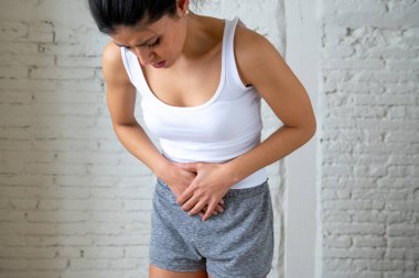 Genç bir kadının karnı üzerinde el ele tutuşarak acı karın ağrısı olan kapatın. Vücut ağrı, gastrit, kabızlık, adet ağrısı ve adet krampları. Sağlık kavramı