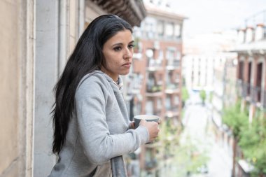 Güzel latin kadın bir fincan kahve bir balkonda evde tutan depresyon muzdarip. Üzgün, acı ve keder bakıyordu. Kriz, depresyon ve ruh sağlığı kavramı