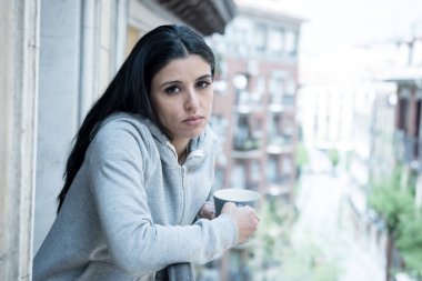 Güzel latin kadın bir fincan kahve bir balkonda evde tutan depresyon muzdarip. Üzgün, acı ve keder bakıyordu. Kriz, depresyon ve ruh sağlığı kavramı