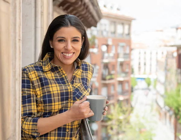 Güleryüzlü ve sıcak kahve ilk fincan gün evde açık balkon keyfi içme İspanyol kadın. Kentsel arka plan. Ev konfor yaşam tarzı