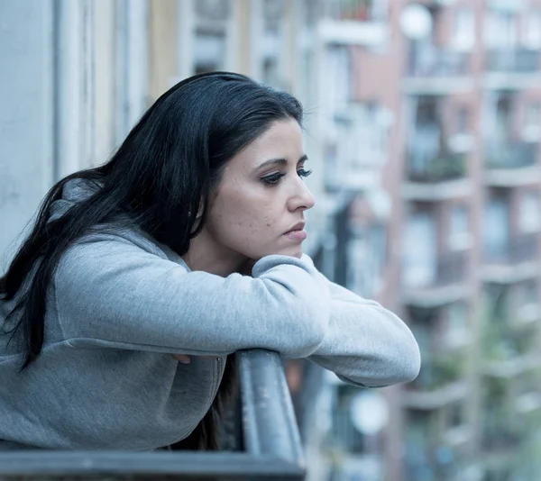 Güzel latin depresif yalnız kadın üzgün bakarak ağrı ve bir balkonda evde endişeli. Kriz, depresyon ve ruh sağlığı kavramı