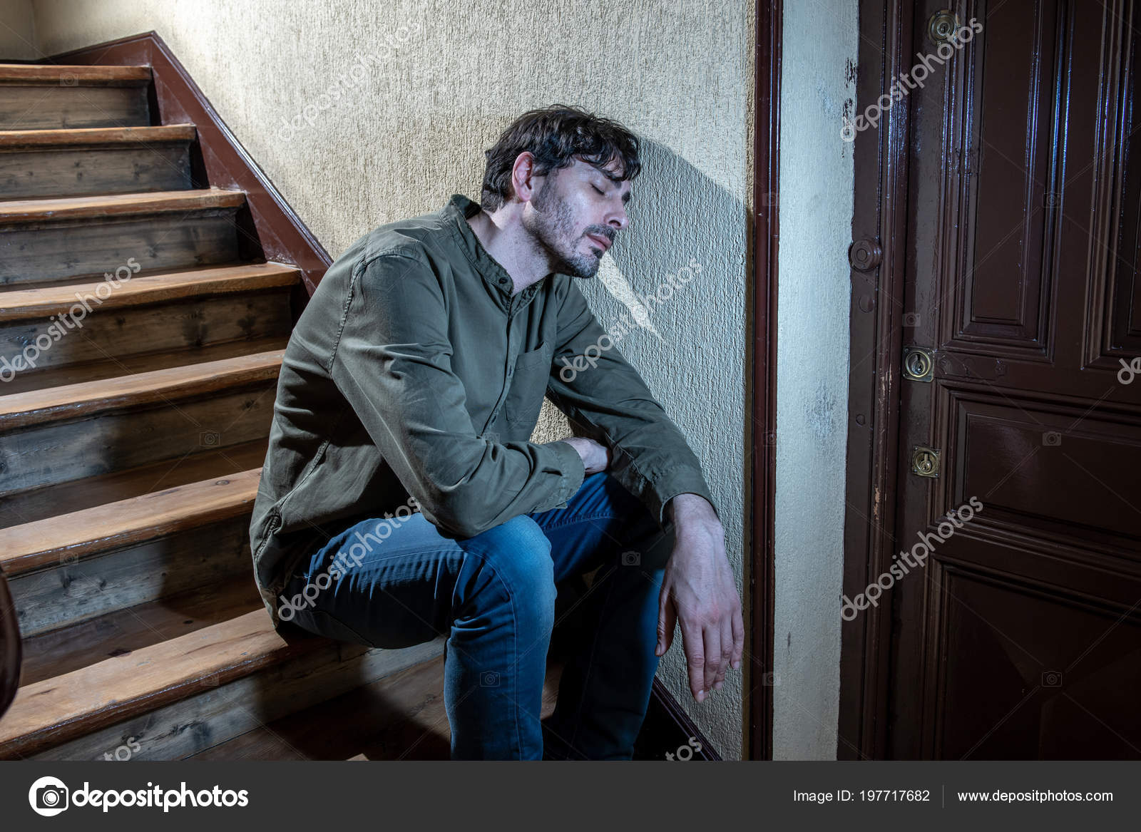 depressed latin man sitting head hands stairwell feeling lonely sad