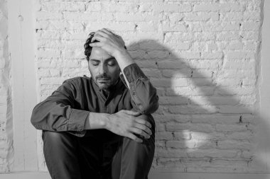 sefil, yalnız ve üzgün ruh sağlığı depresyon kavramı içinde duygu duvardaki bir gölge ile beyaz bir duvar karşı evde oturan genç depresif adam