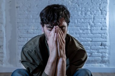 sefil, yalnız ve üzgün ruh sağlığı depresyon kavramı içinde duygu duvardaki bir gölge ile beyaz bir duvar karşı evde oturan genç depresif adam