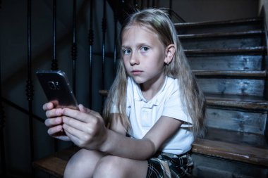 Yalnız, mutsuz, umutsuz ve istismar duygu merdivenlerde oturan mobil akıllı telefon tarafından cyberbullying üzgün depresif genç kız kurbanı. Kısa mesajla zorbalık. Karanlık ışık