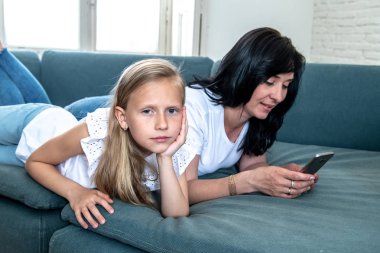Digital technology addicted mum using her smart phone ignoring her sad Little girl feeling abandoned and unhappy with her mum not paying attention to her. Phone addiction and parenting behavior. clipart