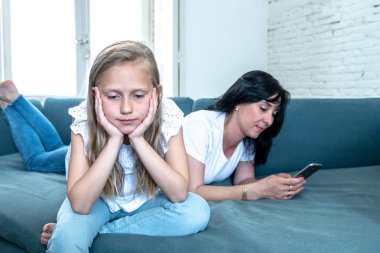 Digital technology addicted mum using her smart phone ignoring her sad Little girl feeling abandoned and unhappy with her mum not paying attention to her. Phone addiction and parenting behavior. clipart
