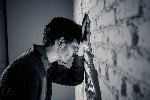 悲しい 疲れたメンタルヘルスうつ病概念で不安を感じて落ち込んでの男を自宅で暗い部屋で白い壁にもたれ — ストック写真