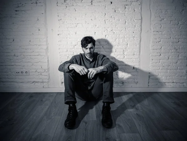 年轻郁闷的男子坐在一个白色的墙上 在家里墙上的阴影感到悲惨 孤独和悲伤的精神健康抑郁症的概念 — 图库照片