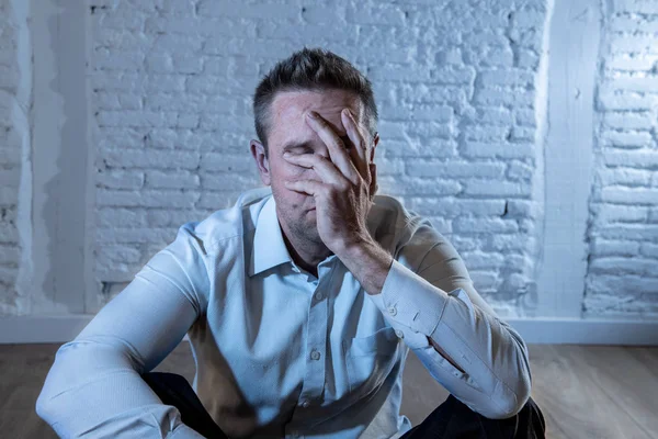 depressed business man feeling sad, lonely and suffering from anxiety leaning on a white wall at home in mental health depression concept