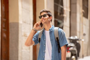 Açık havada Avrupa şehirde ayakta, cep telefonu üzerinde konuşurken, mutlu ve heyecanlı seyir çekici genç adam. Kentsel arka plan. İletişim teknolojisi kavramı.