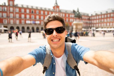 Mutlu ve heyecanlı eğleniyor çekici erkek İspanyol turist Plaza Mayor, Madrid, İspanya'selfie ile smartphone alarak. Seyahat, tatil, tatil Avrupa şehri kavram.