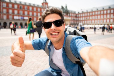 Mutlu ve heyecanlı eğleniyor çekici erkek İspanyol turist Plaza Mayor, Madrid, İspanya'selfie ile smartphone alarak. Seyahat, tatil, tatil Avrupa şehri kavram.