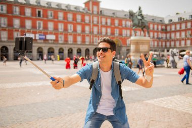 Mutlu ve heyecanlı eğleniyor çekici erkek İspanyol turist Plaza Mayor, Madrid, İspanya'selfie ile smartphone alarak. Seyahat, tatil, tatil Avrupa şehri kavram.