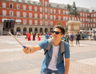 Mutlu ve heyecanlı eğleniyor çekici erkek İspanyol turist Plaza Mayor, Madrid, İspanya'selfie ile smartphone alarak. Seyahat, tatil, tatil Avrupa şehri kavram.