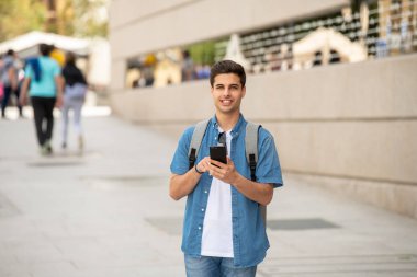 Genç erkek öğrenci Caddesi modern Avrupa şehri, mesaj Smartphone cep telefonu ile olan ayakta kot denim giysiler açık atış