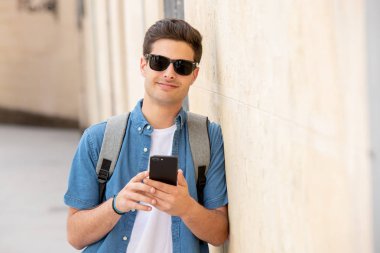 Genç erkek öğrenci Caddesi modern Avrupa şehri, mesaj Smartphone cep telefonu ile olan ayakta kot denim giysiler açık atış