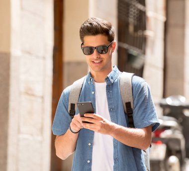 Genç erkek öğrenci Caddesi modern Avrupa şehri, mesaj Smartphone cep telefonu ile olan ayakta kot denim giysiler açık atış