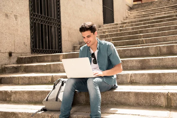 屋外階段に座りながらノート パソコンを使用してスマート カジュアルな服装で若いハンサムな現代人 学生やフリーランサー屋外インターネットをサーフィン — ストック写真