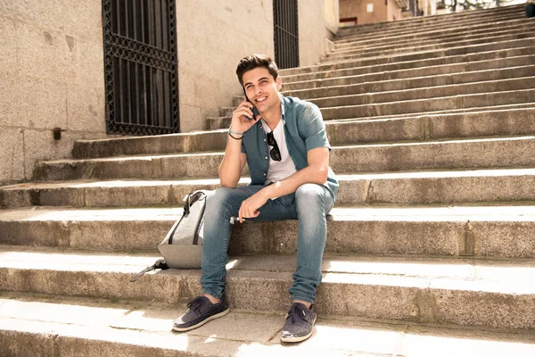 Atraktivní Mladý Muž Sedí Schodech Venku Mluvit Mobilním Telefonu Šťastný — Stock fotografie