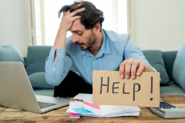 Laptop ile evde çalışma, sinirli ve endişeli genç adam bir yardım işareti faturaları seyir ve ev finansman kavramında fatura ödeme holding