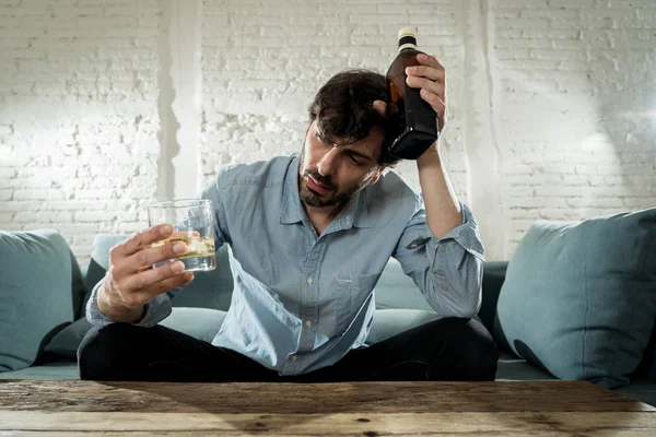 醉酒的酒鬼说谎的商人喝威士忌从瓶子和玻璃郁闷浪费和悲伤在家沙发上酗酒和酗酒的概念 — 图库照片