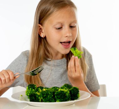 Onun brokoli sebze yeme mutlu genç sarışın kız. sağlıklı çocuk beslenme kavramı