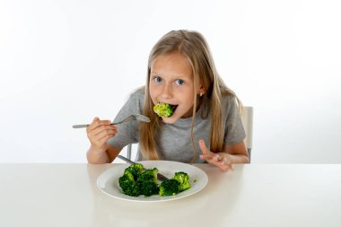 Onun brokoli sebze yeme mutlu genç sarışın kız. sağlıklı çocuk beslenme kavramı