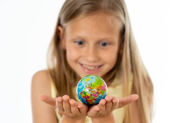 Gülümseyerek, dünya öğrenme kavramı içinde beyaz arka plan üzerinde duran sevimli sevimli küçük kız bir küre tutan odak dışı.