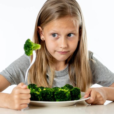 Beslenme ve sağlıklı beslenme alışkanlıkları çocuklar sağlıklı beslenme kavramı için. Çocuk sebze yemeyi sevmiyorum. Küçük sevimli kız beyaz bir arka plan üzerinde sağlıklı brokoli yemek reddediyorum