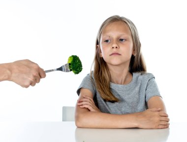 Nutrition and  healthy eating habits for kids healthy eating concept. Child does not  not like to eat vegetables. Little cute kid girl refusing  to eat healthy broccoli vegetables on a white background