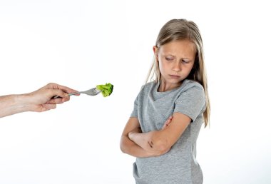 Nutrition and  healthy eating habits for kids healthy eating concept. Child does not  not like to eat vegetables. Little cute kid girl refusing  to eat healthy broccoli vegetables on a white background clipart