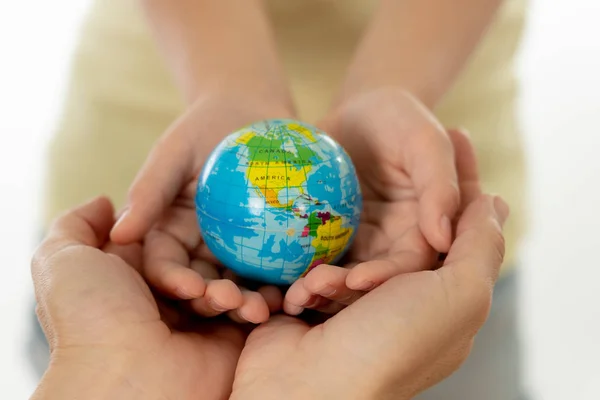 close up photo of mother and child holding hands with a world globe in their hands in better world idea protection and education concept