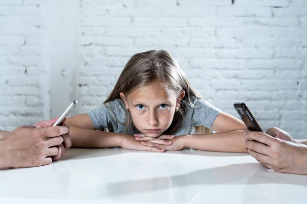 mother and father using mobile phones neglecting little sad ignored daughter bored and lonely feeling abandoned and disappointed with  parents.  mobile cell smart phone addiction bad behavior concept