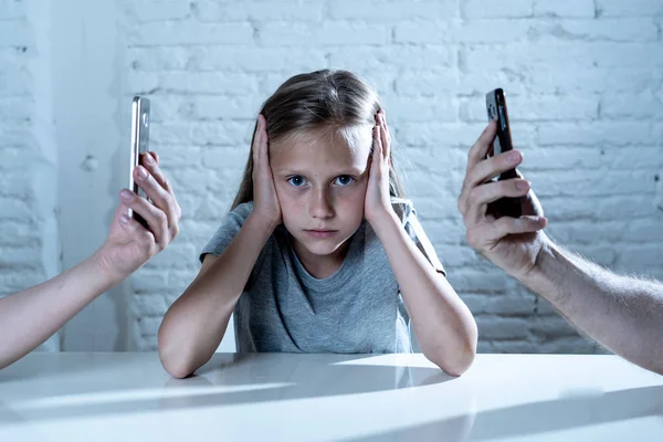 mother and father using mobile phones neglecting little sad ignored daughter bored and lonely feeling abandoned and disappointed with  parents.  mobile cell smart phone addiction bad behavior concept