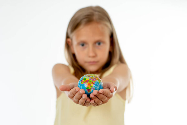 Charming cute little girl out of focus holding a globe,  smiling, standing on white background in world learning concept.