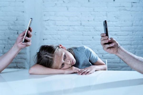 mother and father using mobile phones neglecting little sad ignored daughter bored and lonely feeling abandoned and disappointed with  parents.  mobile cell smart phone addiction bad behavior concept