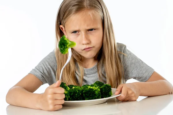 Nutrition and  healthy eating habits for kids healthy eating concept. Children do not like to eat vegetables. Little cute kid girl refuse to eat healthy broccoli  on a white background