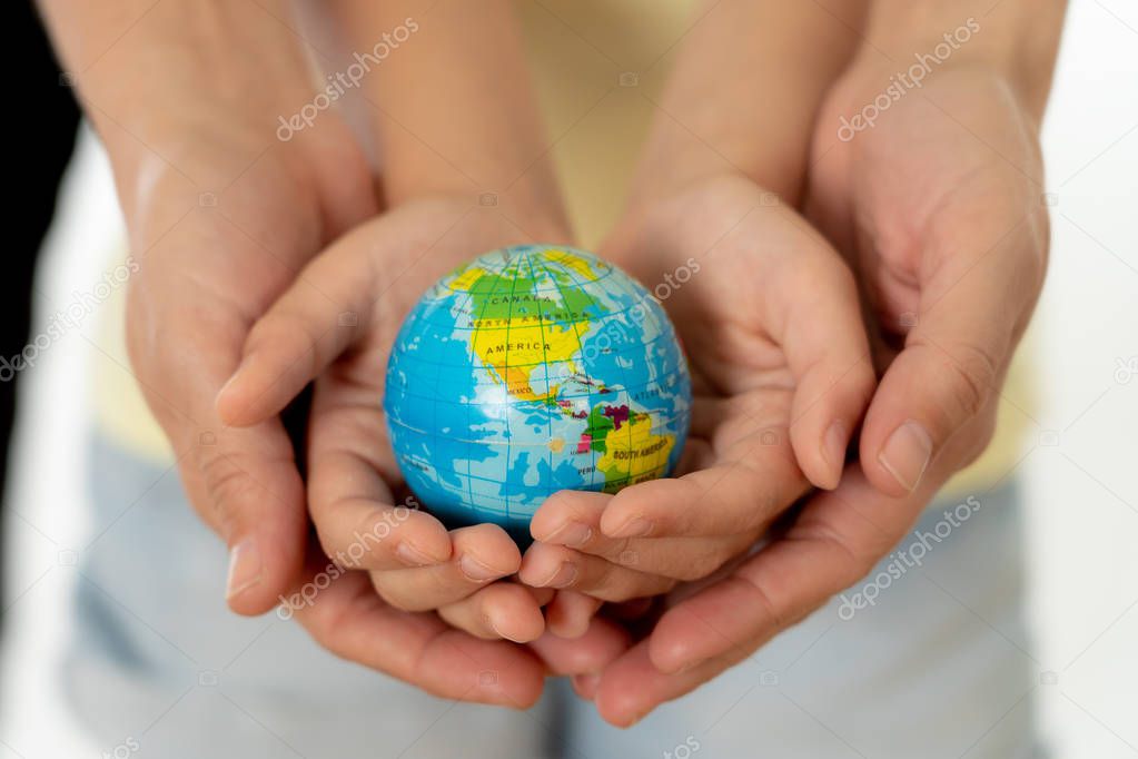 close up photo of mother and child holding hands with a world globe in their hands in better world idea protection and education concept