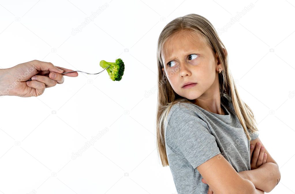 Nutrition and  healthy eating habits for kids healthy eating concept. Child does not  not like to eat vegetables. Little cute kid girl refusing  to eat healthy broccoli vegetables on a white background