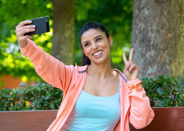 iyi ince yetişkin seksi uygun seyir spor egzersiz yaptıktan sonra bir modern şehir parkı sabah sportif latin kadın olun selfie telefonunu fitness ve