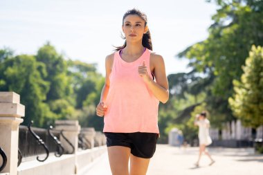 Güneşli parlak ışık kadın fitness modeli eğitim dışında şehir yeşil park geçiş eğitim fitness egzersiz kavramı içinde koşu acı çalışan kadın runner