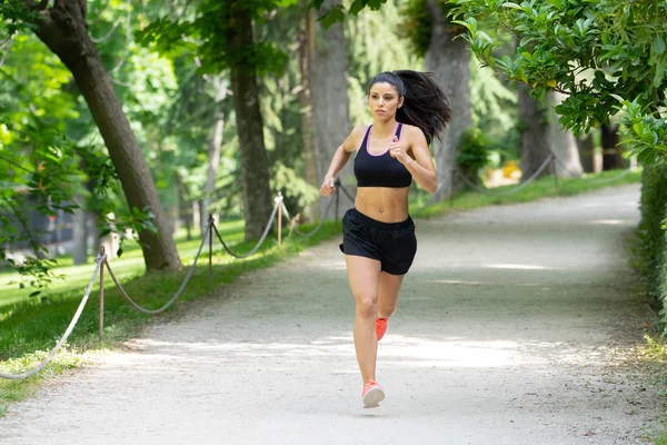 Güneşli parlak ışık kadın fitness modeli eğitim dışında şehir yeşil park geçiş eğitim fitness egzersiz kavramı içinde koşu acı çalışan kadın runner